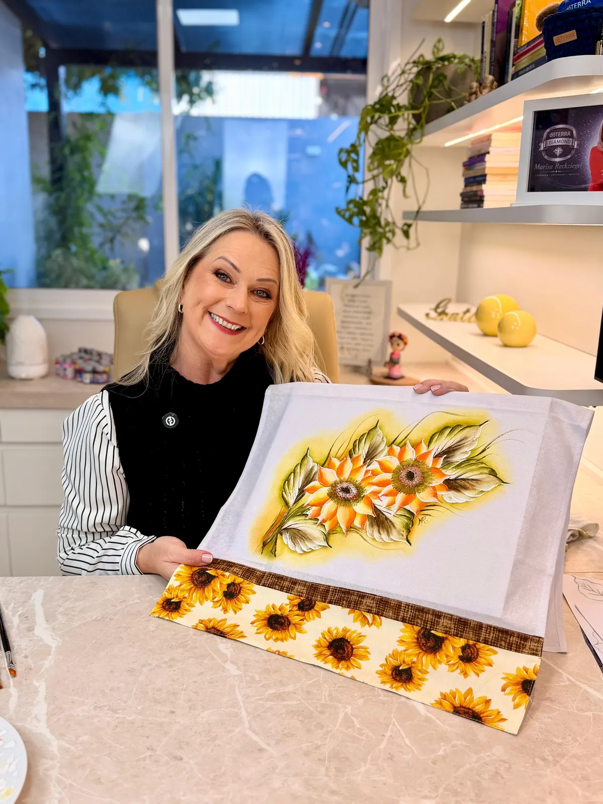 Marisa Reckziegel segurando um pano pintado com girassóis
