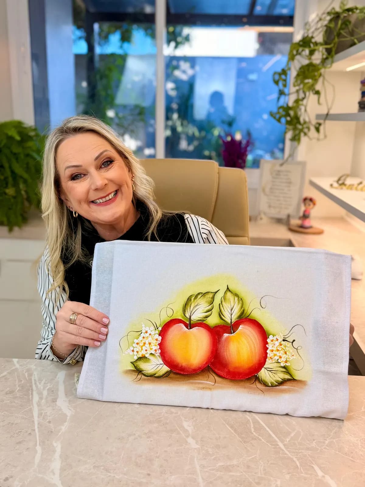 Marisa Reckziegel segurando um pano pintado com maçãs