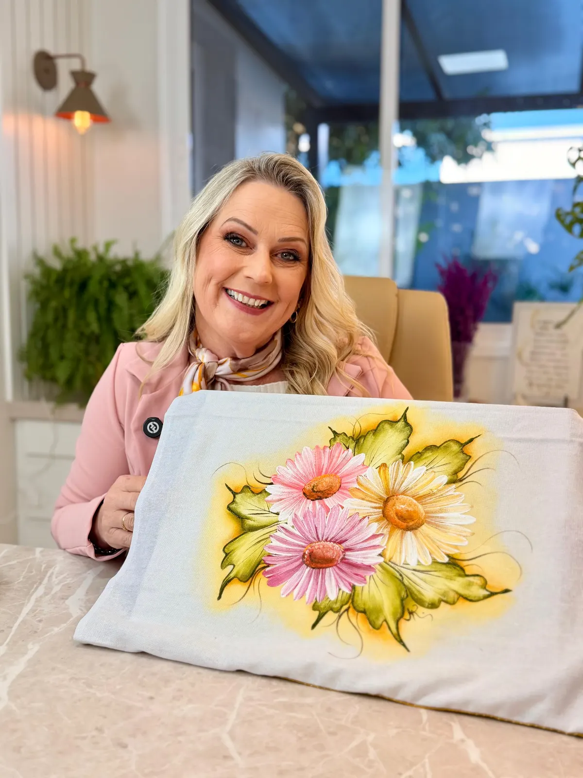 Marisa Reckziegel segurando um pano pintado com margaridas